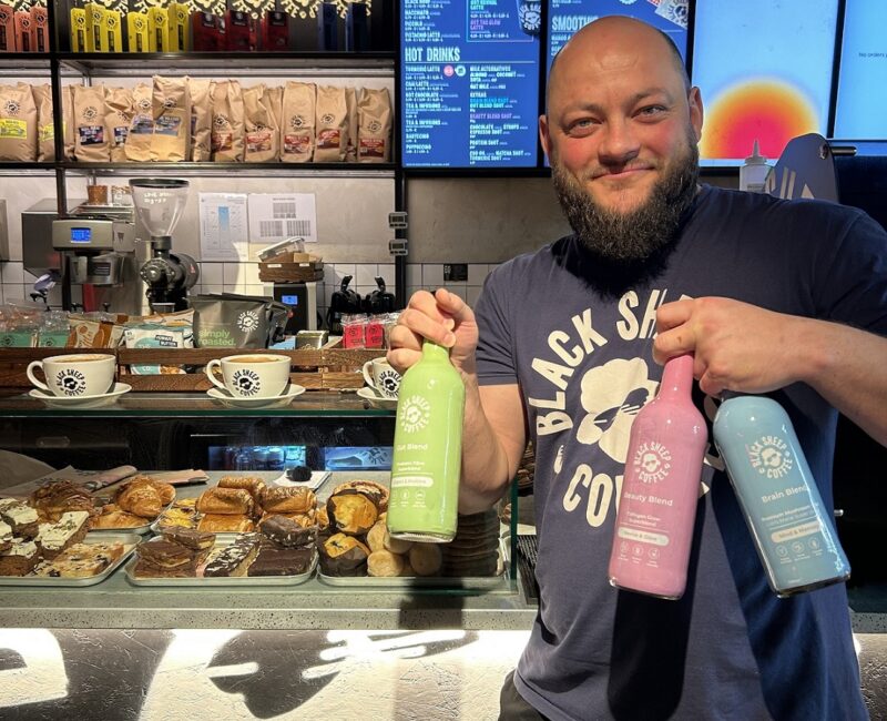 Black Sheep Coffee barista holding the three syrup bottles that make up the Functional Coffee range.