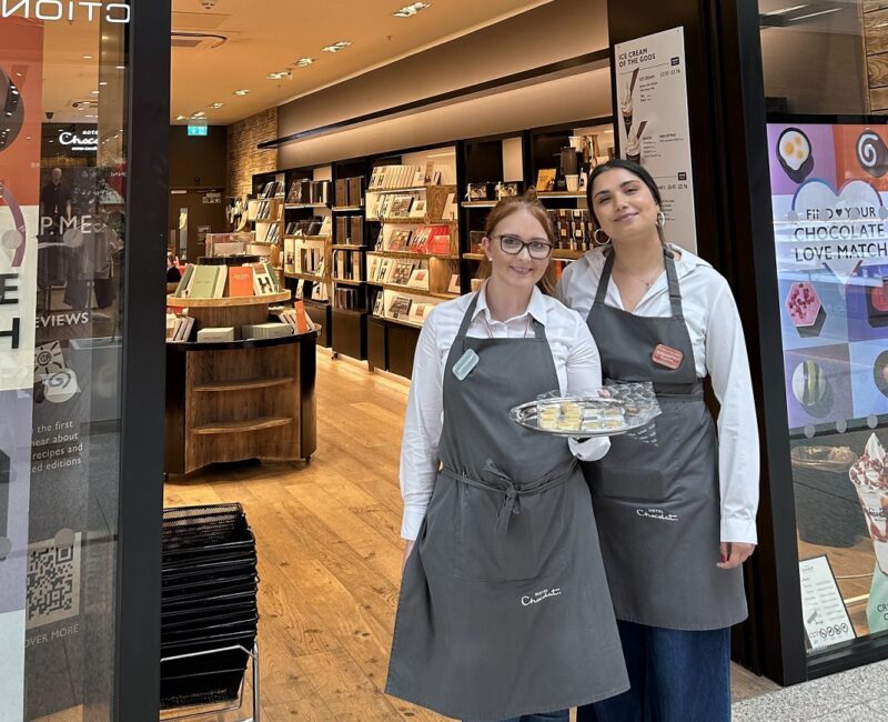 Two friendly and smiling Hotel Chocolat staff stood outside their store in ManchesterArndale