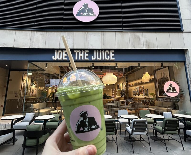 Someone holding a iced matcha outside Joe and the Juice store