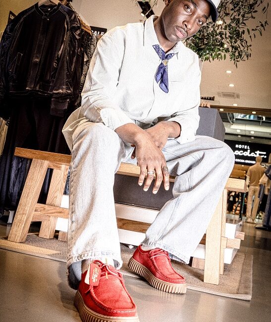 Man wearing long sleeve shirt and trousers and bright red shoes.