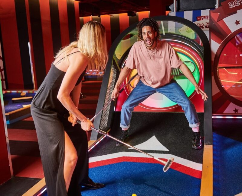 A man and a woman playing mini golf