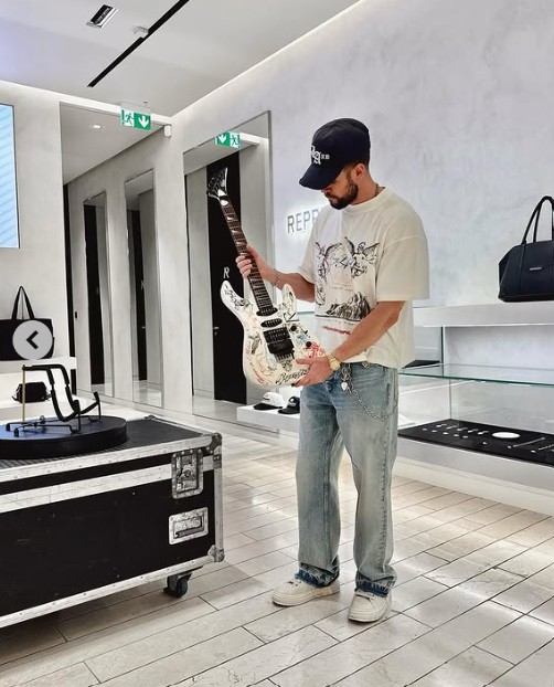 Man holding a customer painted white guitar inside Represent
