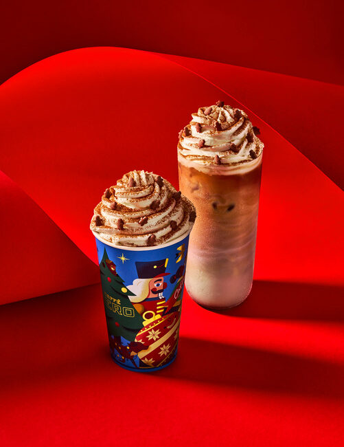 Two drinks from Caffe Nero, one hot and in a festive cup holder, the other is ices with cream on top.